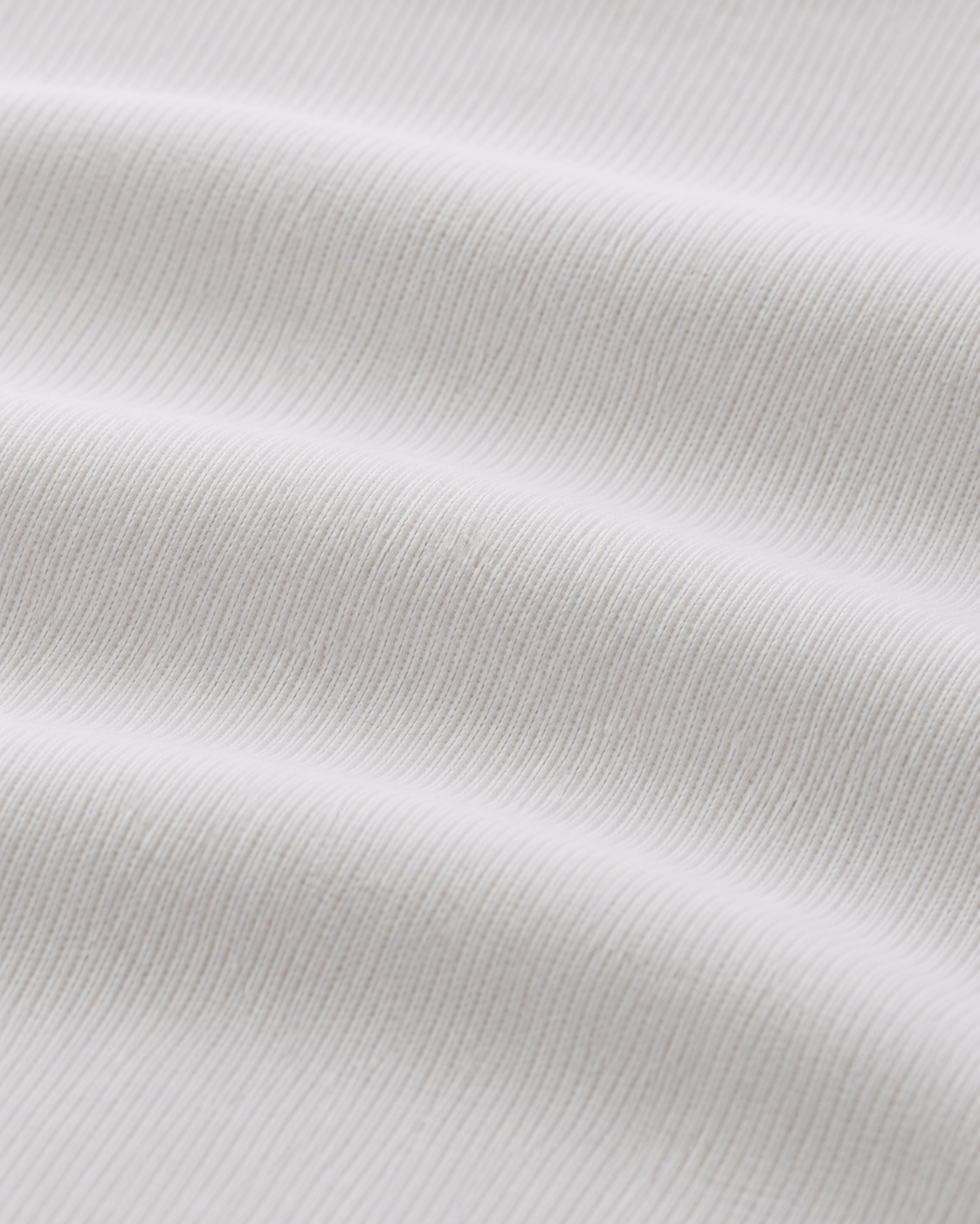 Nahaufnahme der gerippten weißen Stoffstruktur des ÜRON Signature Henley.